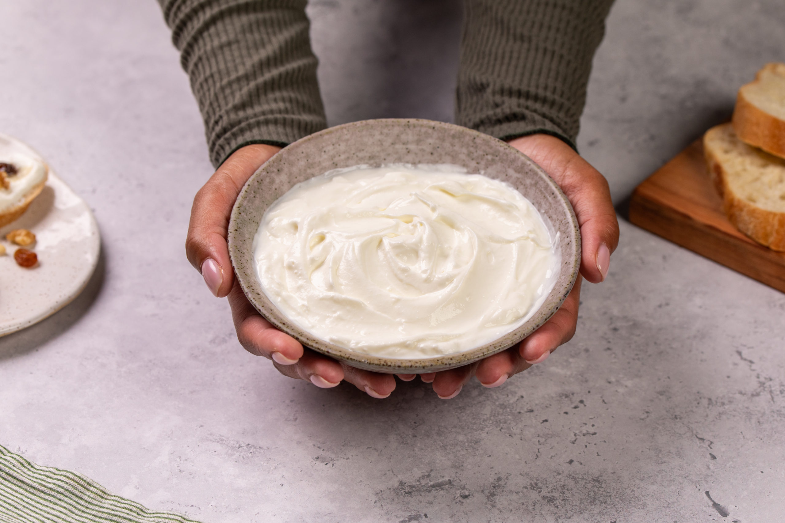 Hands holding bowl of labneh yogurt