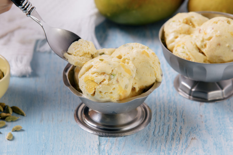 Scoops of mango kulfi indian ice cream on blue counter
