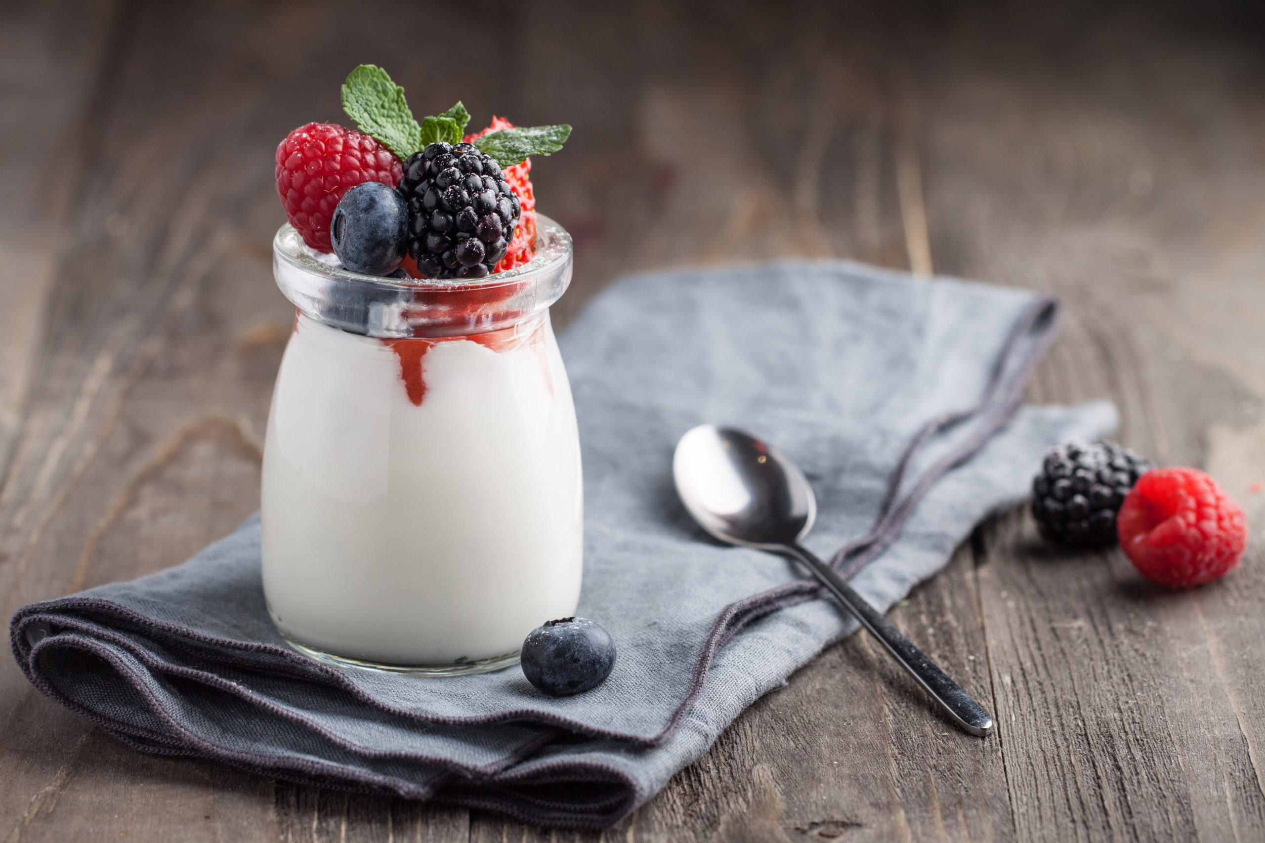 jar of panna cotta with berries and mint leaf