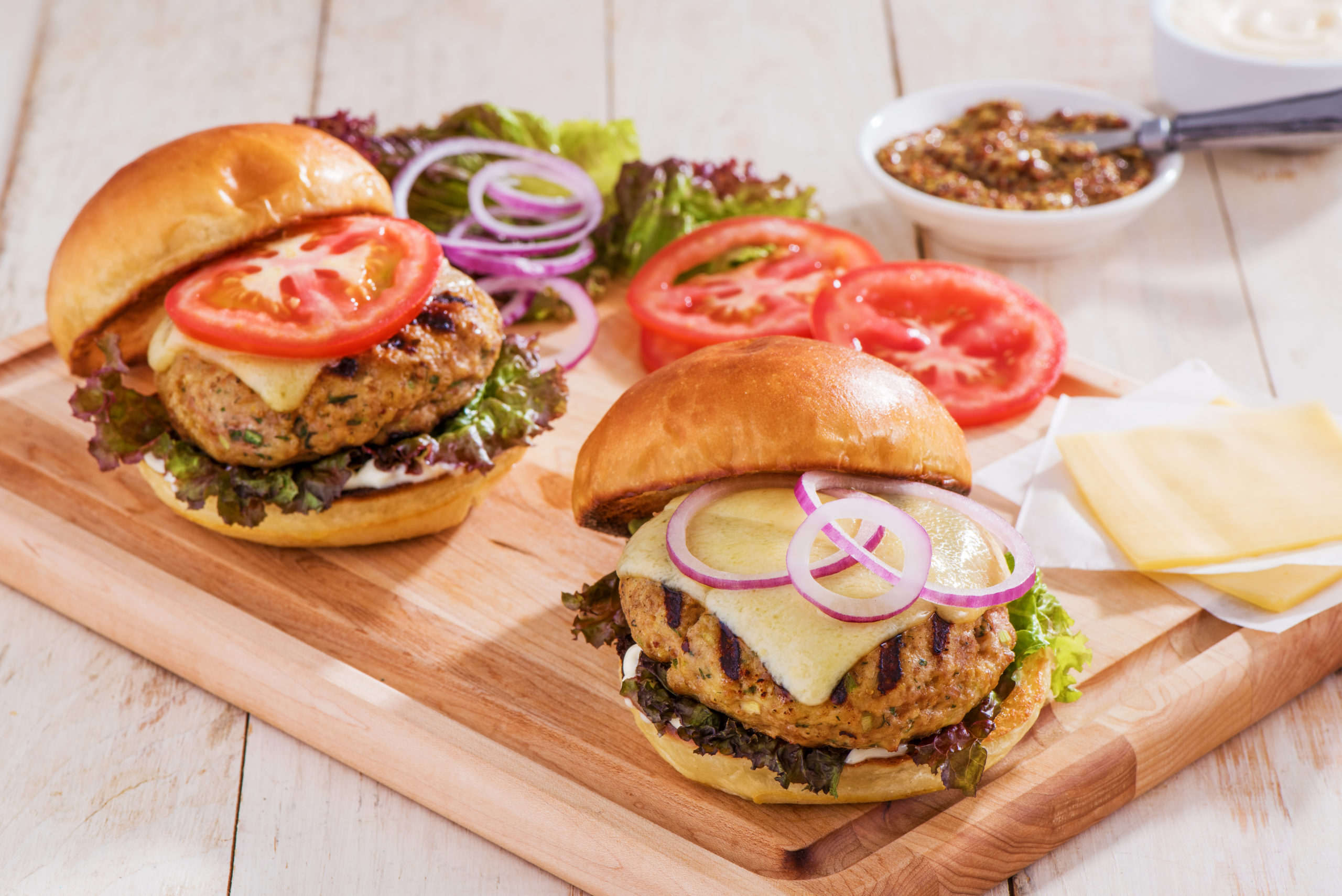 Turkey cheeseburgers with toppings on a wood board