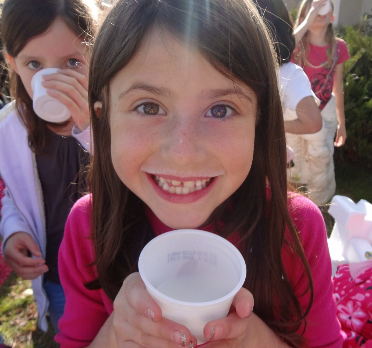 Enthusiastic girl drinking milk at school from a cup