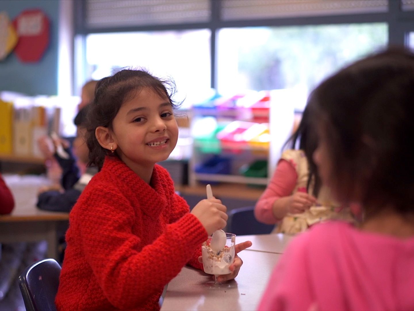 Kindergarten student smiling and enjoying a yogurt parfait