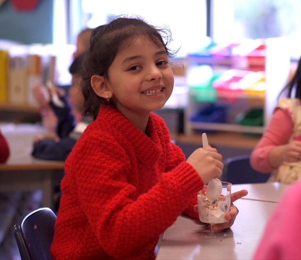 Kindergarten student smiling and enjoying a yogurt parfait