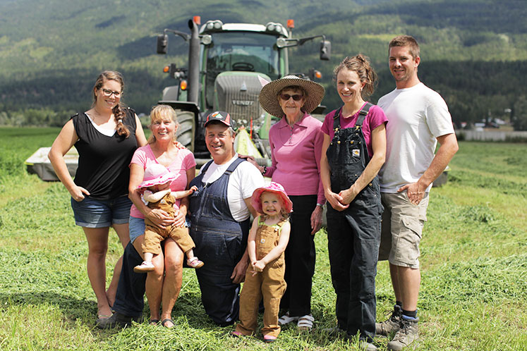 Family of dairy farmers standing in front of tractor