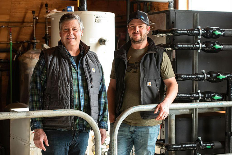 Abe and AJ Stobbe, dairy farmers in Mara, BC standing in front of the geothermal heat exchange system that heats their milking parlour and their homes