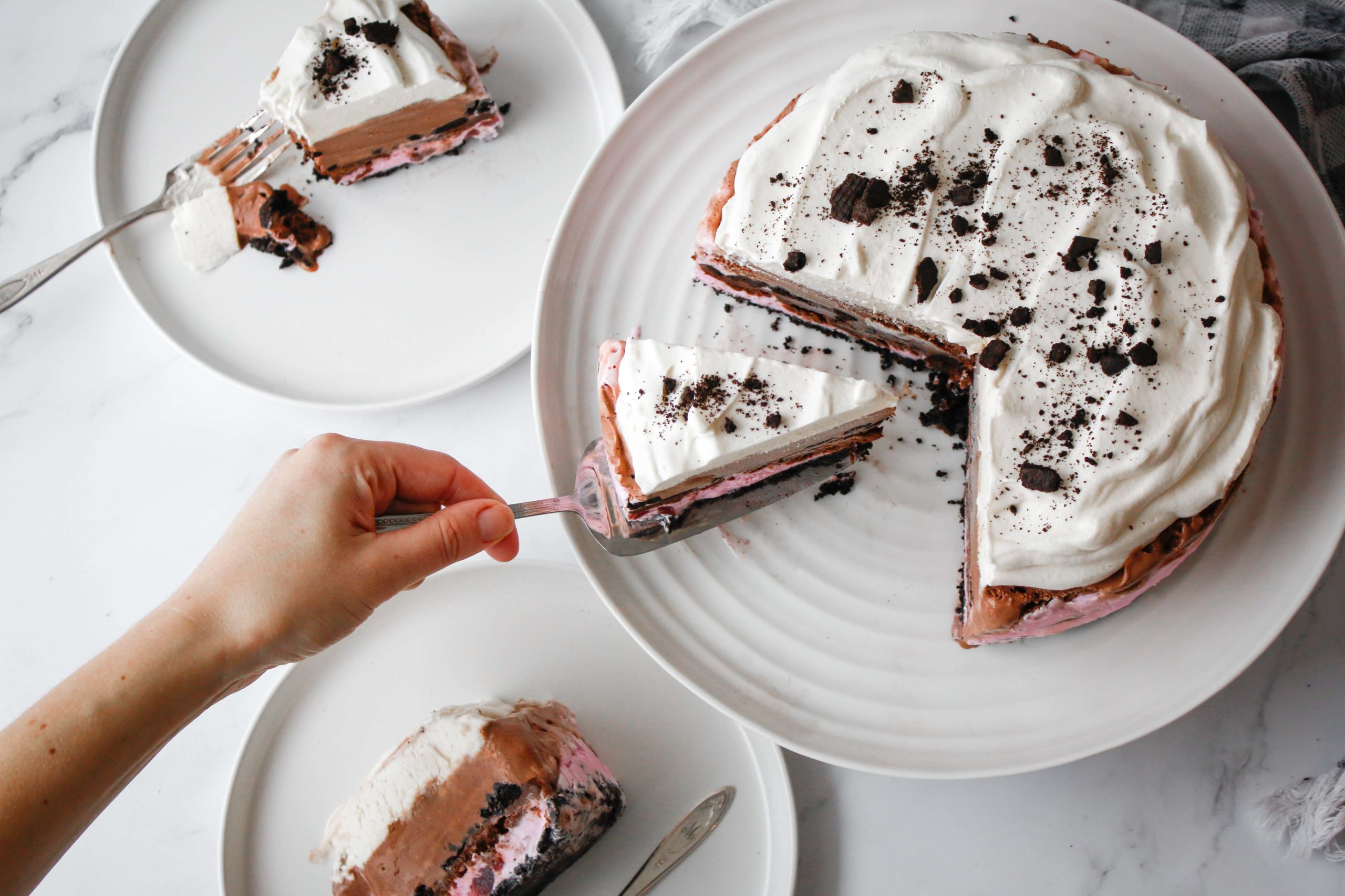 Cutting slices of ice cream cake topped with cookie crumble.