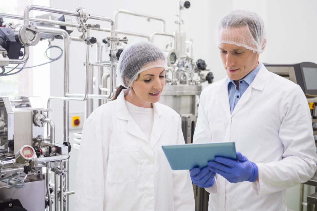 Two workers looking at a tablet in dairy processing plant