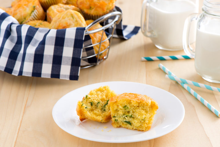 basket of cheddar jalapeno muffins with a glass of milk