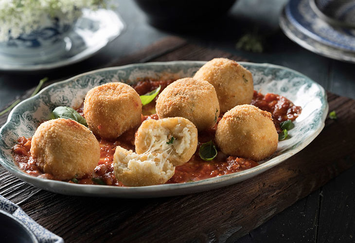 Arancini with tomato sauce on blue plate
