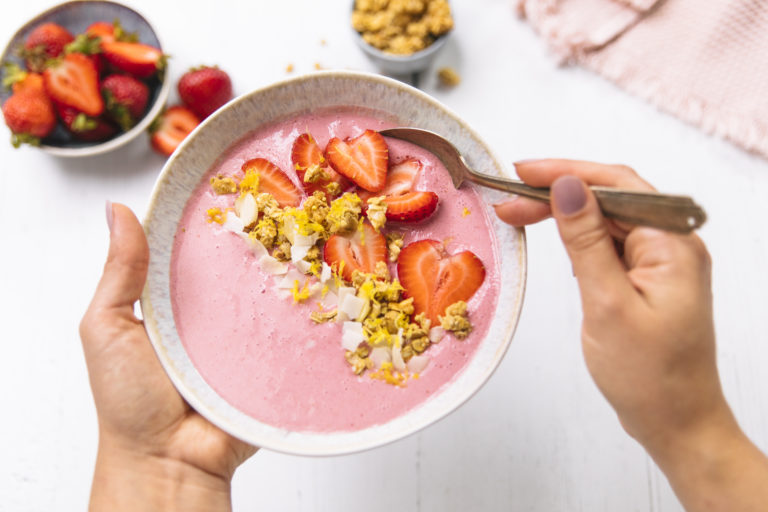 strawberry smoothie bowl with sprinkled granola and strawberry toppings.