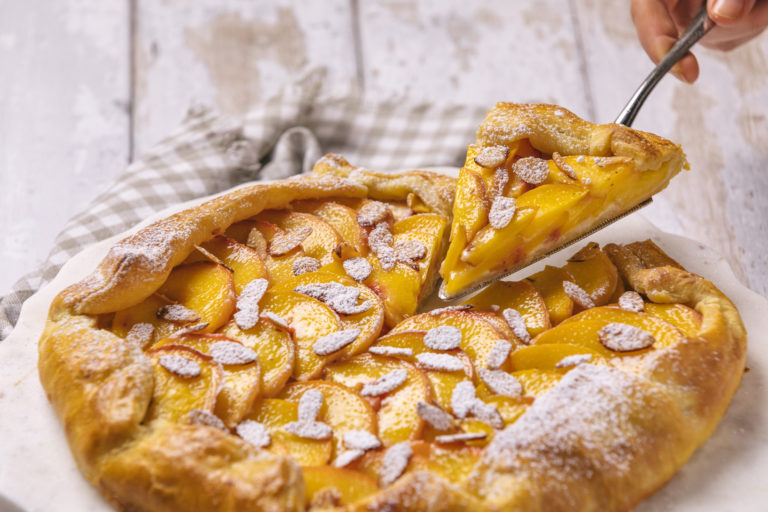 peach galette and checkered napkin on wooden backdrop