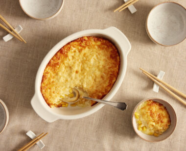 Baking dish of cheese corn pie with serving bowls and chopsticks