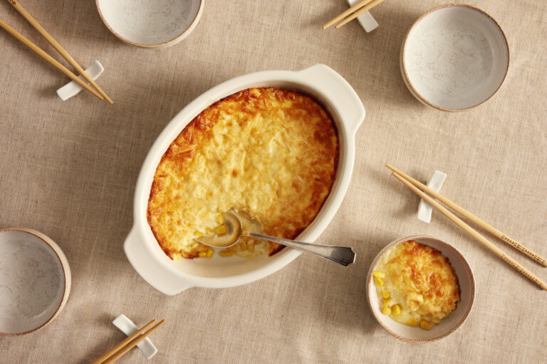 Baking dish of cheese corn pie with serving bowls and chopsticks