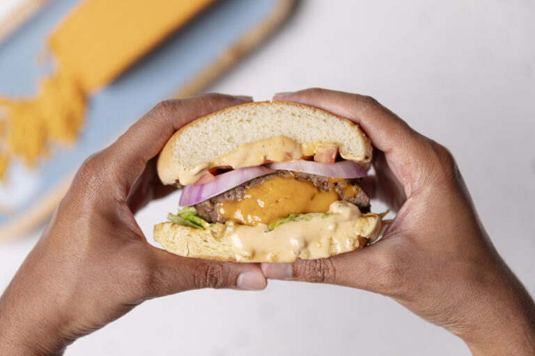 two hands holding a stuffed cheddar burger