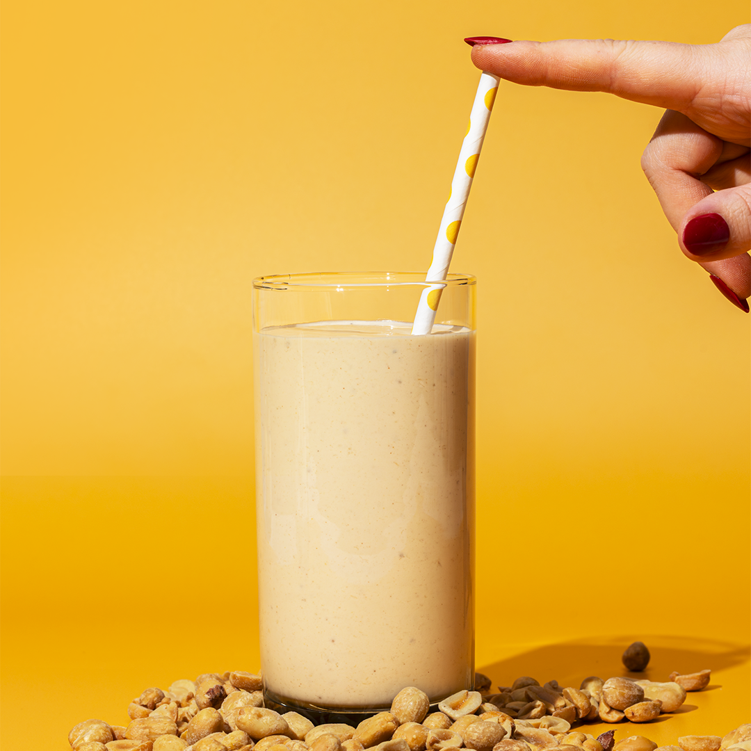 glass of peanut butter smoothie with a side of peanuts