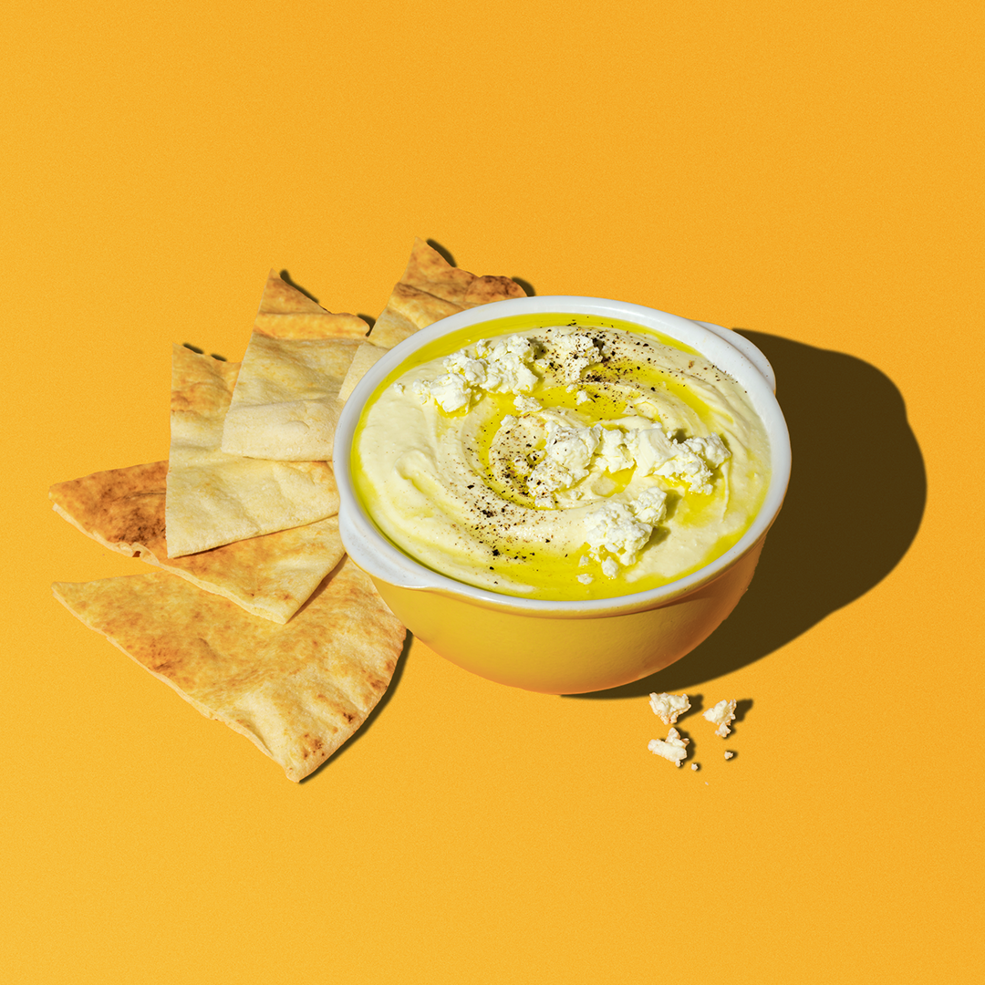 bowl of whipped feta, tahini dip with a drizzle of olive oil and side of pita chips