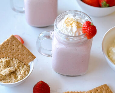 glasses of strawberry cheesecake smoothies with graham crackers and strawberries on the side