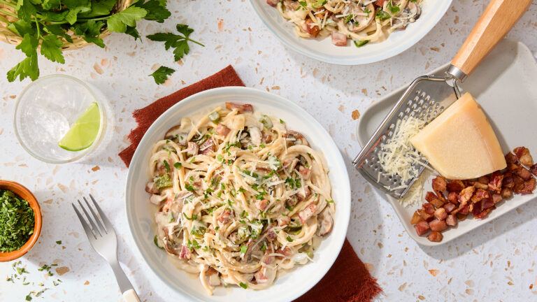 plate of pasta carbonara with a side of cheese and bacon