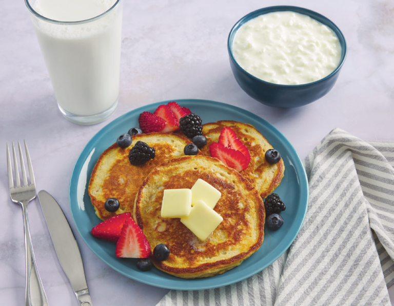 Pancakes on a plate with a side of milk and cottage cheese