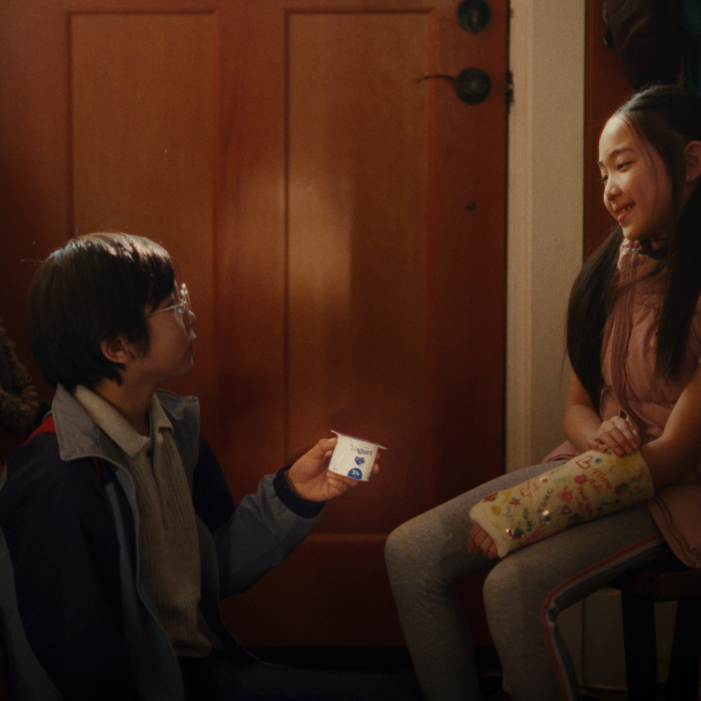 boy handing yogurt to sister