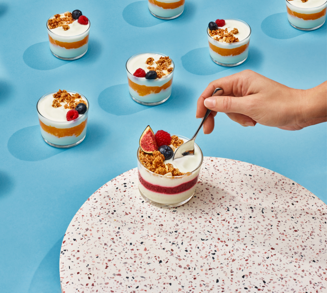 hands scooping into yogurt parfait