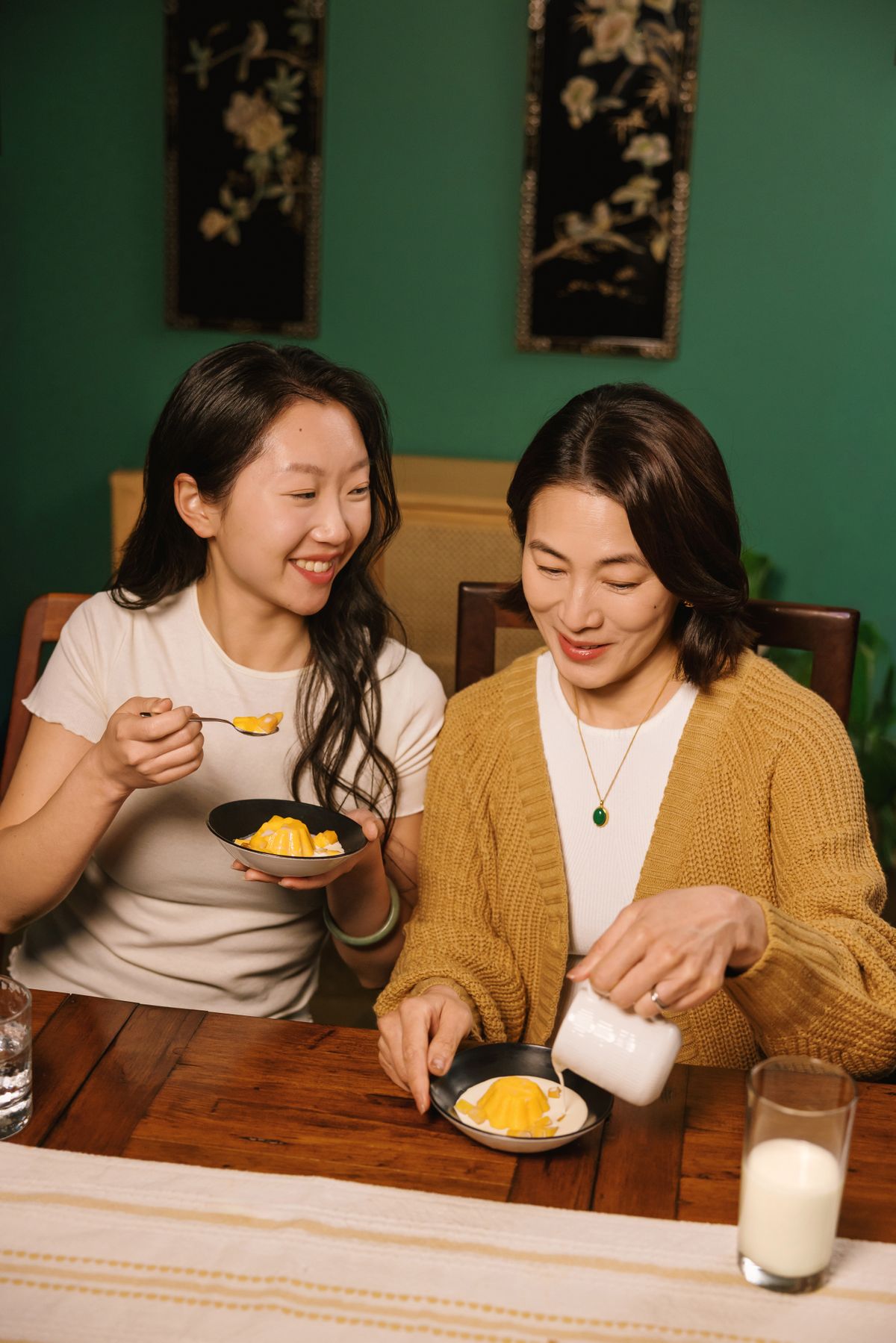 Mother and daughter enjoying mango pudding with fresh cream.
